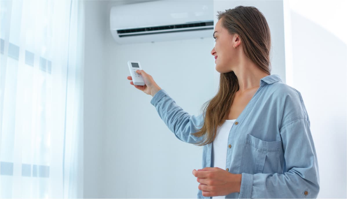 Woman using a remote control to change temperature on ductless heat and ductless air pump