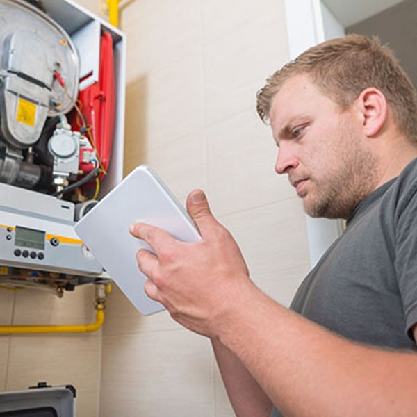 Technician repairing Gas Furnace using digital tablet Technician using tablet to help run diagnostic work on unit