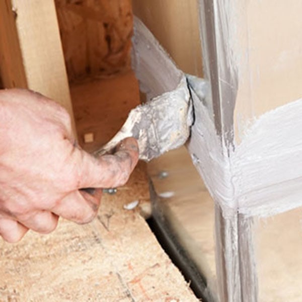 Technician patching damaged air duct using putty.