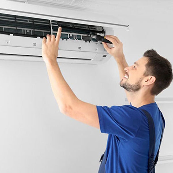 Ductless System 1_600x600 A technician services a white Mitsubishi Electric ductless air conditioning unit mounted on a white wall.