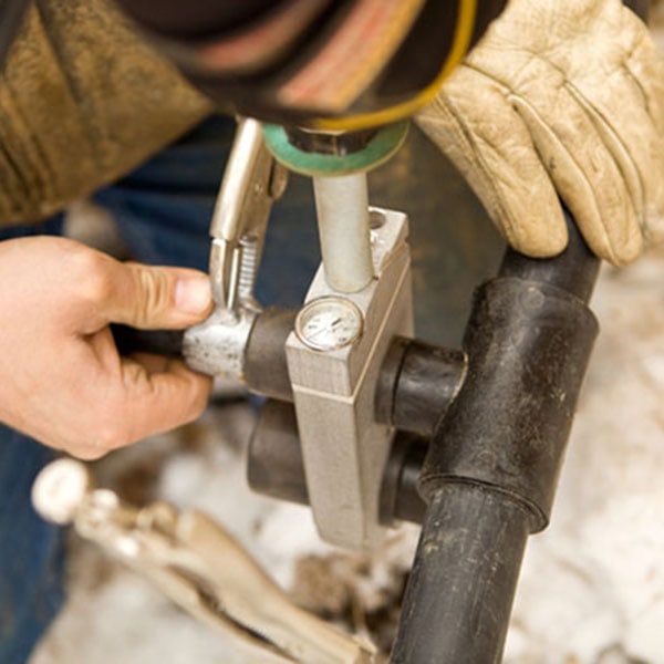 Individual fixing a pipe with a pipe wrench, highlighting work related to geothermal heat pump systems.