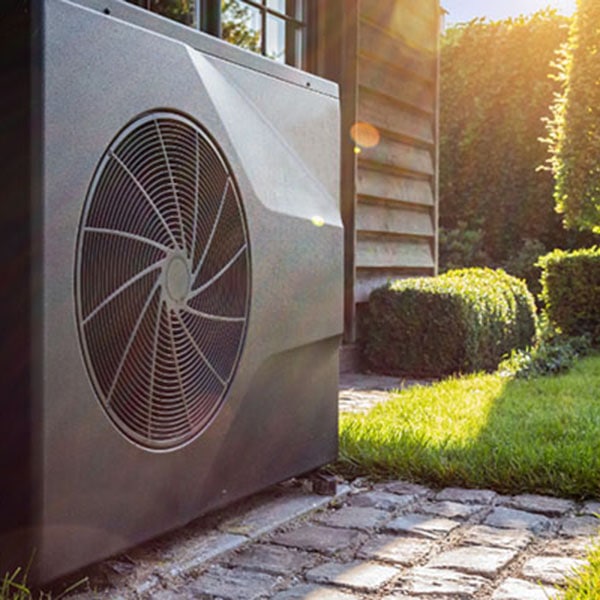A garden scene featuring a heat pump, highlighting its installation beside a residential home.