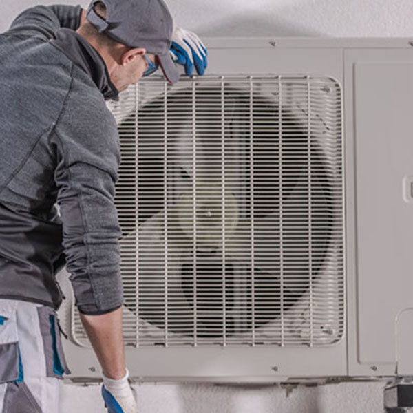 A technician is repairing an air conditioner, focusing on heat pump maintenance for optimal performance.