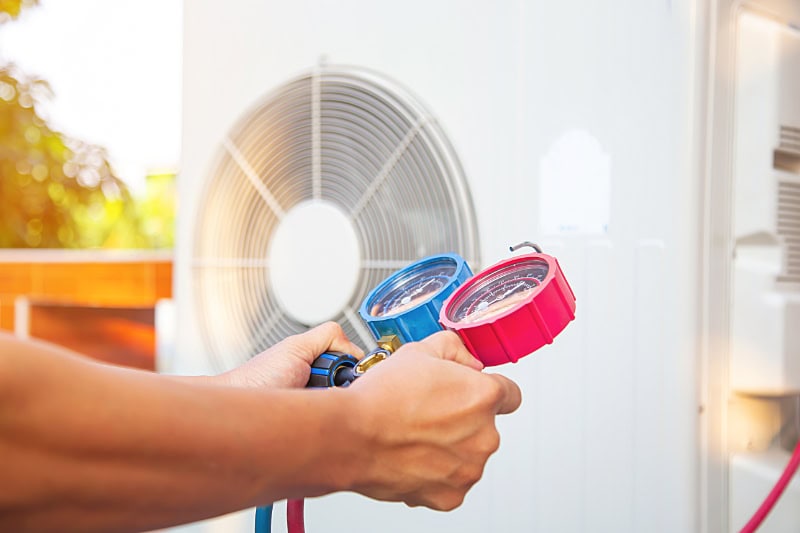 Hands of Technician are using a measuring tool to check Vacuum pump evacuates air for air conditioner.