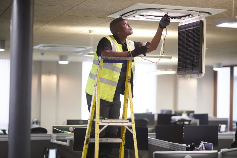 Female maintenance technician performing air conditioning service.