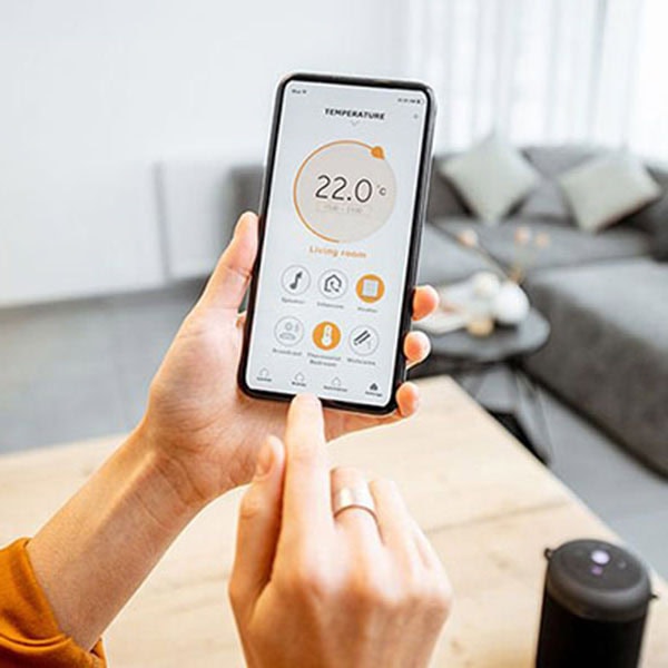 A woman uses her smartphone to monitor the temperature in her home, illustrating the convenience of home automation.
