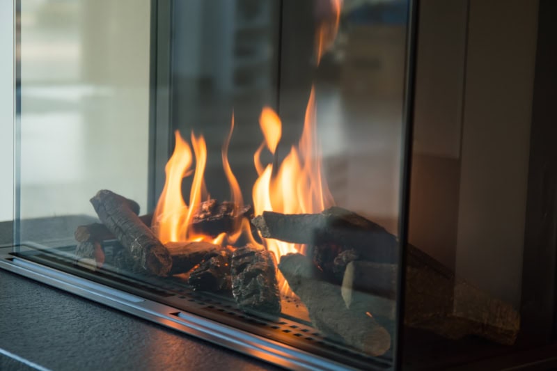 a fire burns in a glass fireplace, radiates heat.