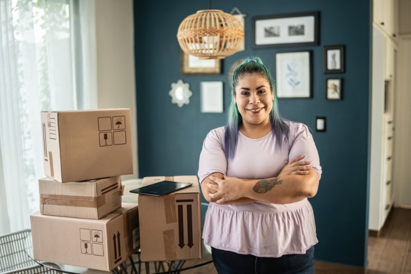 What Is Radon and Why Is It Bad? Portrait of mid adult woman with packages at home.