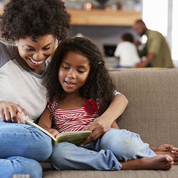 Oil Furnaces 1_600x600 A mother and her daughter share a moment on the couch, reading a book together in a warm and inviting space.
