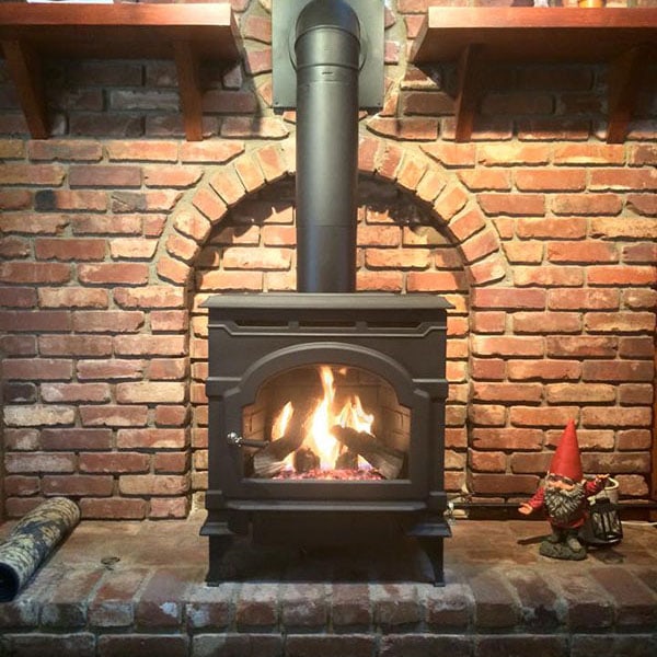A cozy brick fireplace with a pellet-burning stove, showcasing pellet stove and insert services available.