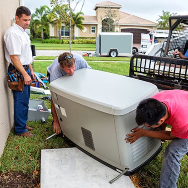 Three men servicing a whole-house generator outside a house.